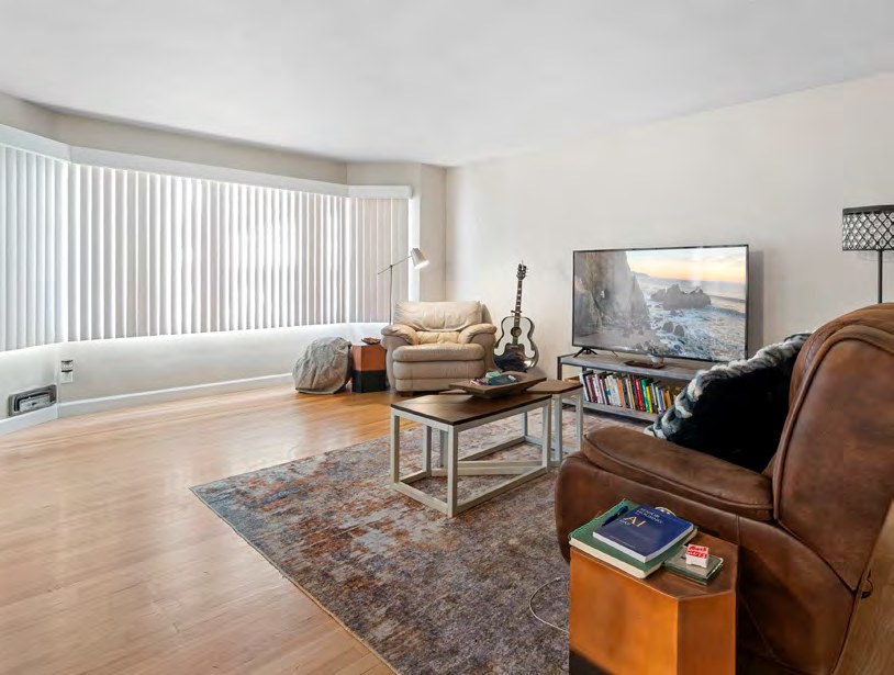 Interior view of a living room with hardwood floors, a leather armchair, and a television