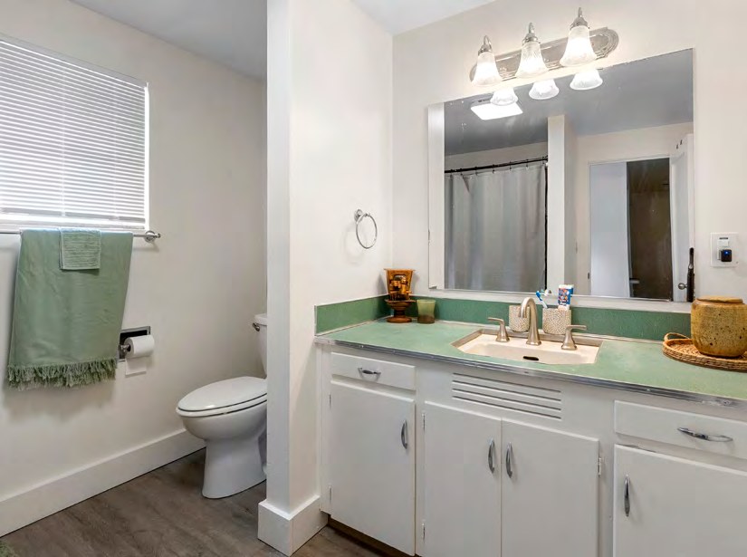 Interior view of a bathroom with a vanity, mirror, and toilet