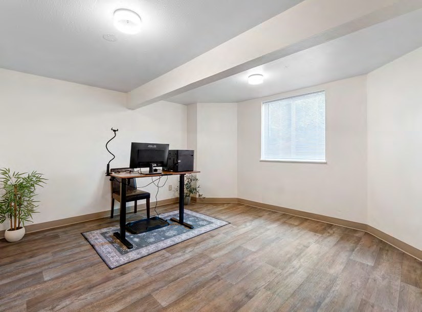 Interior view of a room with hardwood floors, a desk, and a window